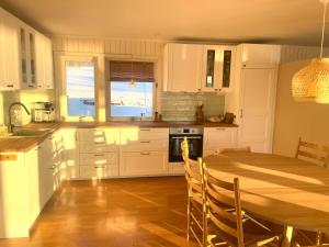 a kitchen with white cabinets and a table with chairs at Aurora beach house in Trondalen