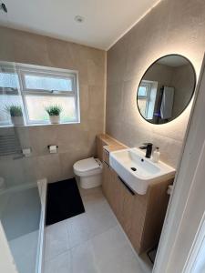 a bathroom with a sink and a toilet and a mirror at Adrian Cottage in Abbots Langley +10 photos