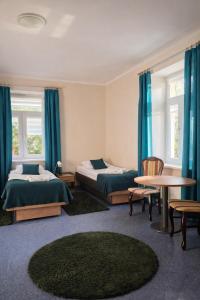 two beds in a room with blue curtains and a table at Zacisze Nad Nidą Resort in Pińczów