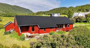 a red barn with a black roof in a field at Aurora beach house in Trondalen