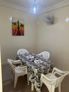 ein Esszimmer mit einem Tisch und weißen Stühlen in der Unterkunft Résidence Dëkando in Malika
