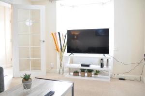 a living room with a flat screen tv on a white entertainment center at Beaney View House - Comfortable Spacious 4 Bedrooms En-suites House with Free Wifi and Parkings Located at quiet neighbourhood and easy access to town centre in Swindon