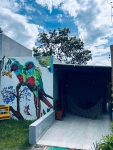 a mural of three parrots on a wall at Chalé do galo in São Domingos