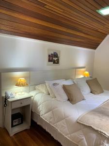 a bedroom with a white bed with a wooden ceiling at SPA LIFESTYLE Centro de Bem Estar in Canela