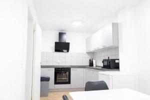 a white kitchen with white appliances and a table at LETA Homes - Komfortable FeWo mit Traumbalkon mit flexiblem, Self-Check-In & eigenen Parkplätzen in Straubing +3 photos