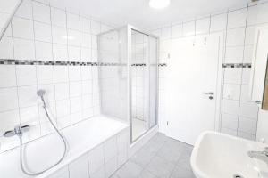 a white bathroom with a shower and a tub and a sink at LETA Homes - Komfortable FeWo mit Traumbalkon mit flexiblem, Self-Check-In & eigenen Parkplätzen in Straubing