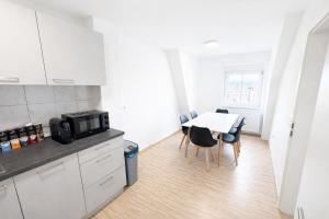a kitchen with a table and chairs and a microwave at LETA Homes - Komfortable FeWo mit Traumbalkon mit flexiblem, Self-Check-In & eigenen Parkplätzen in Straubing