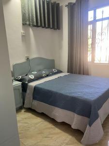 a bedroom with a bed with a blue comforter and a window at TecTec 2 Appartment 1 in Pereybere