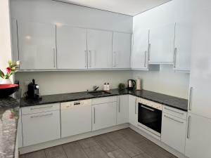a white kitchen with white cabinets and black counter tops at Residenza Acapulco II by Fewotessin in Moscia