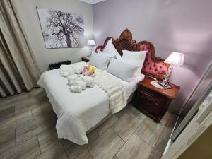 a bedroom with a large white bed with a wooden headboard at A Pearl Place in Pretoria