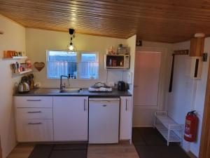 a kitchen with white cabinets and a sink and a refrigerator at Vonarland hús með einu svefnherbergi in Stokkseyri +15 photos