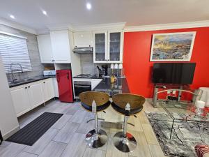 a kitchen with a red wall and two stools at A Pearl Place in Pretoria