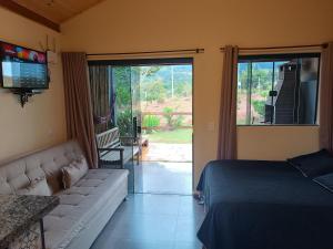 a bedroom with a bed and a couch and a sliding glass door at Refúgio São Tomé in São Thomé das Letras