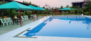 a large pool with blue water and chairs and umbrellas at Hotel mountain garden in Tingo María