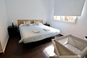 a bedroom with a bed with a chair and a window at La abuela Pepa Fácil Aparcamiento in Mérida