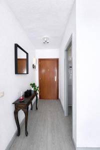 a hallway with a table and a wooden door at Apartamento Benalmádena costa, Torremuelle in Benalmádena
