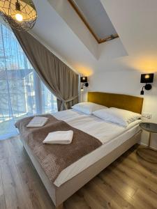 a bedroom with a large bed with two towels on it at Białe Tarasy in Rogowo
