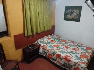 a bedroom with a bed with a flowered blanket and a window at Hotel el Dorado La Candelaria in Bogotá