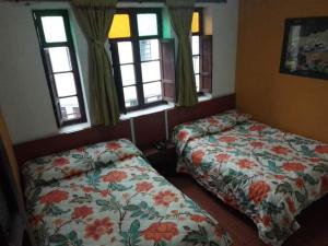 a bedroom with two beds and windows in it at Hotel el Dorado La Candelaria in Bogotá