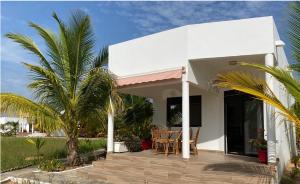 a white house with a porch with a table and chairs at Residence Coco Plage in Elinkinde +113 photos