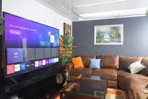 a living room with a couch and a large screen tv at Warm & Luxury Stay at Maboneng with Kingbed HugeTV WiFi in Johannesburg