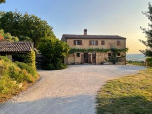 an old stone house on a gravel driveway at L'Infinito in Mombaroccio