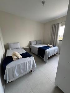 a bedroom with two beds with towels on them at Refúgio Vila Mar Apto in Imbituba
