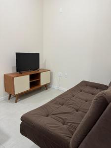 a living room with a couch and a flat screen tv at Refúgio Vila Mar Apto in Imbituba