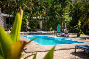 a man sitting on a bench next to a swimming pool at Koba Apartments Santa Teresa in Santa Teresa Beach