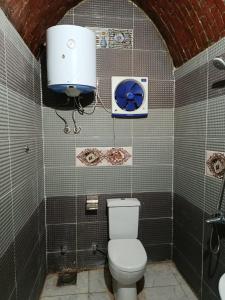 a bathroom with a toilet and a clock on the wall at Rooma ka Guest House in Aswan