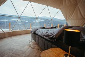 a bedroom with a bed in a room with large windows at Glamping Pod Hradom súkromné jacuzzi a sauna in Bardejov