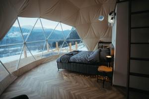 a bedroom with a bed in a tent with a large window at Glamping Pod Hradom súkromné jacuzzi a sauna in Bardejov