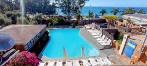 an overhead view of a swimming pool with lounge chairs and the ocean at Hotel Huasco in Huasco