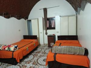 two beds in a room with orange sheets at Rooma ka Guest House in Aswan +18 photos