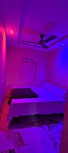 a bedroom with purple lighting and a bed with a ceiling at Hotel Mannat palace in Ujjain
