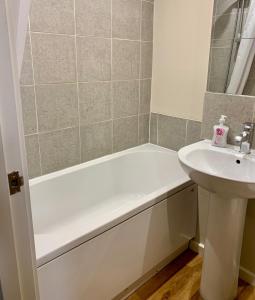 a bathroom with a white tub and a sink at 1 Bed Apartment By Cozy Quarters Property Management Short Term Lets Hartlepool Near Beach in Hartlepool +2 photos