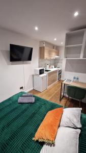 a living room with a bed with a green blanket at Private Studio Suite, 24h Self Check-in in Luton