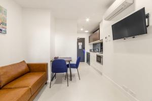 a living room with a couch and a table with chairs at Whitehorse Apartments Hotel in Box Hill