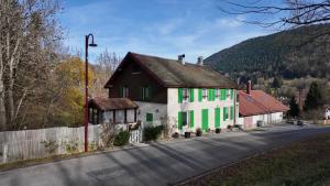a house with green and white paint on the side of a road at Mon Refuge B&B in Jougne