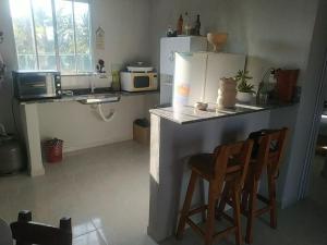 a kitchen with a counter with two chairs and a refrigerator at PÔR Do SOL BEACH in Marataizes