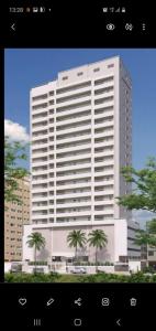 a large white building with palm trees in front of it at Ilha Salinas Canto do Forte in Praia Grande