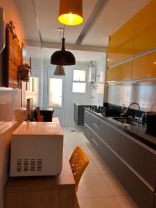 a kitchen with a counter with a microwave on a table at Ilha Salinas Canto do Forte in Praia Grande +12 photos