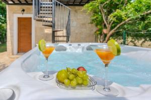 two glasses of juice and fruit on a table in a swimming pool at Villa Nancy with jacuzzi in Benkovac