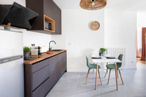 a kitchen with a white table and green chairs at Romantic getaway with jacuzzi, Garden view in Mulhouse