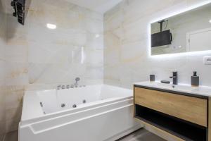 a white bathroom with a tub and a sink at Romantic getaway with jacuzzi, Garden view in Mulhouse +17 photos
