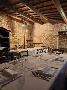 a dining room with white tables and chairs and a brick wall at Castello di Petecciano B&B in Mosciano SantʼAngelo