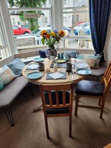 a table with chairs and a vase of flowers on it at Glascoed Guest House in Llandudno