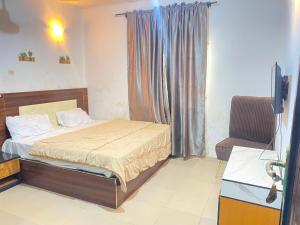 a bedroom with a bed and a window and a chair at Elite Hotel in Ekpoma
