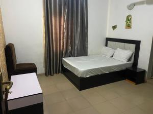 a small bedroom with a bed and a chair at Elite Hotel in Ekpoma