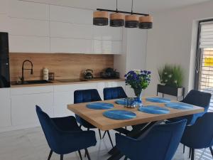 a dining room with a wooden table and blue chairs at Wakacyjna Pokusa in Kroczyce